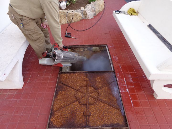 Técnico aplicando un tratamiento con un nebulizador en una tapa de registro del suelo